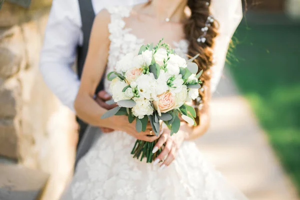 Krásný mladý svatební pár pózuje s kyticí květin v rukou — Stock fotografie