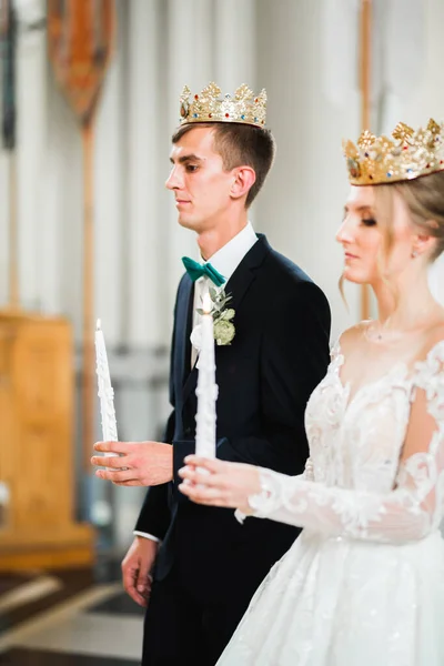 Bride and groom holding candles in church — Stock Photo, Image