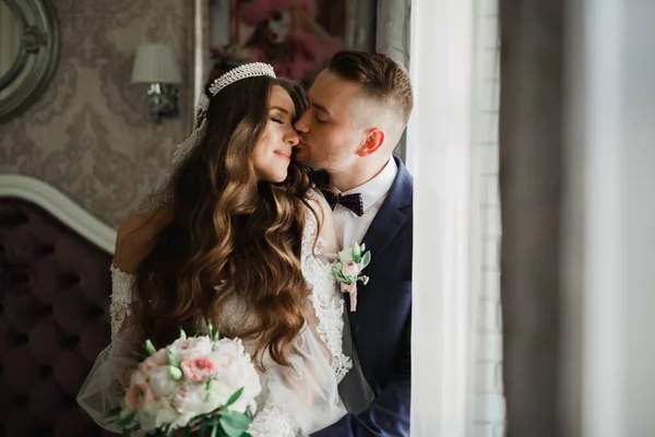 Schönes junges Hochzeitspaar posiert mit Blumenstrauß in den Händen — Stockfoto