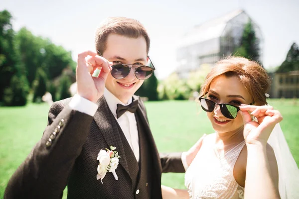 Щаслива весільна пара наречена і наречений посміхаються в сонцезахисних окулярах на природі — стокове фото