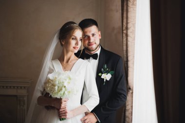 Güzel, genç bir çift ellerinde çiçeklerle poz veriyorlar.