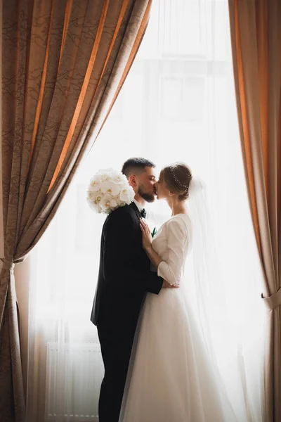 Vacker brud och brudgum omfamnar och kysser på sin bröllopsdag — Stockfoto