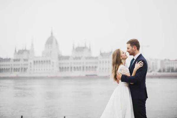 Damada poz veren ve eğlenen güzel bir gelin Budapeşte parlamentosu yakınlarında, mesajlaşmak için yer, düğün çifti — Stok fotoğraf