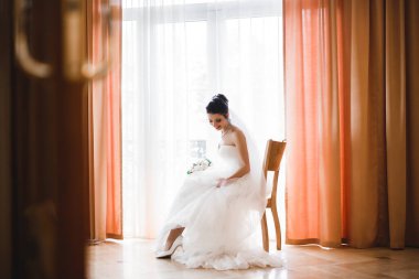 Beyaz elbiseli lüks gelin düğün törenine hazırlanırken poz veriyor.