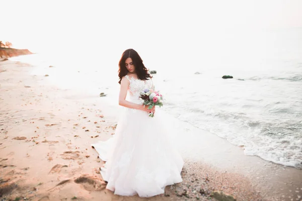 Bella signora, sposa in posa in un abito da sposa vicino al mare al tramonto — Foto Stock