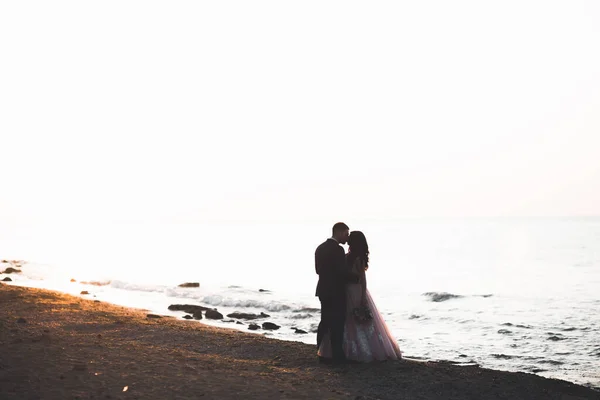 Glückliche und romantische Szene von frisch verheirateten jungen Hochzeitspaaren, die am schönen Strand posieren — Stockfoto