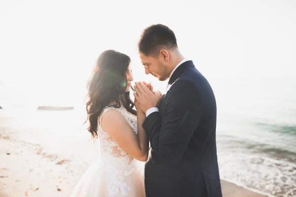 Bröllopspar, brudgum, brud med bukett poserar nära havet och blå himmel — Stockfoto