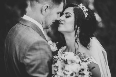 Yeni evli çiftimiz düğün günlerinde ellerinde buketle parkta yürüyorlar.