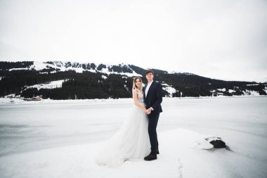 Çift, gelin ve damat dağlarda el ele tutuşuyorlar.