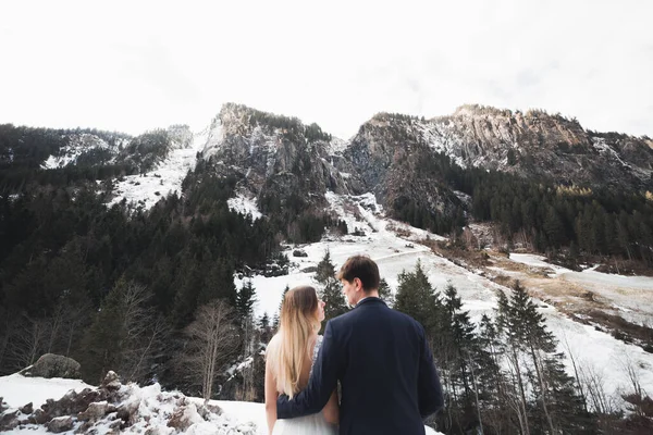 Mooi jong koppel in de winter bergen. Winterwandeling van geliefden. man knuffelen vrouw — Stockfoto