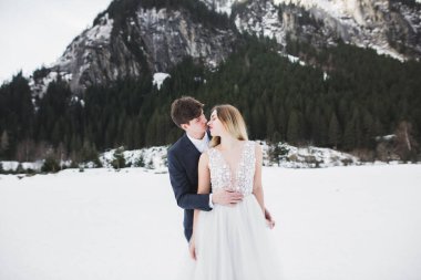 Sadece öpüşen evli bir çift, arka planda karla kaplı dağlar.