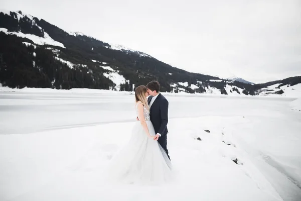 Hermosa pareja joven en las montañas de invierno. Paseo de invierno de los amantes. Hombre abrazando mujer —  Fotos de Stock