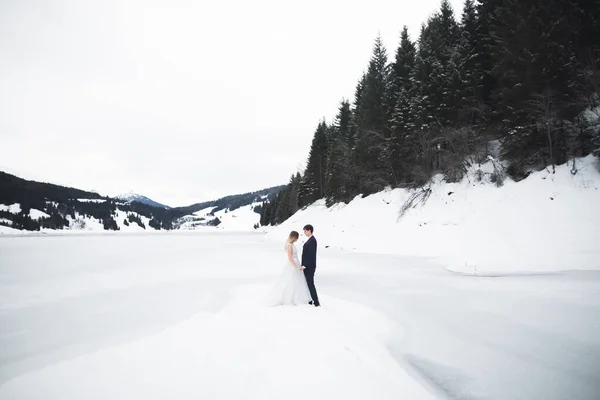 Romantisch jong stel op zoek weg, achteraanzicht, meer en winter bergen op de achtergrond — Stockfoto