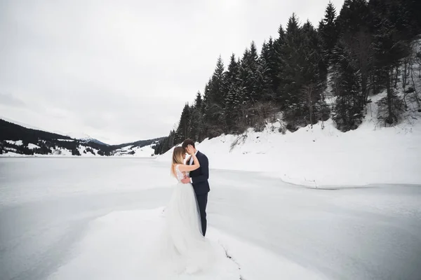 Schönes junges Paar in den Winterbergen. Winterwanderung der Verliebten. Mann umarmt Frau — Stockfoto