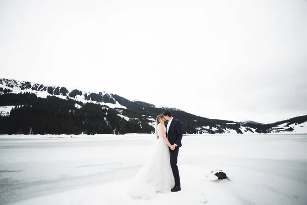 젊고 행복 한 부부가 키스를 하고, 눈덮인 산들 이 배경에 있다 — 스톡 사진