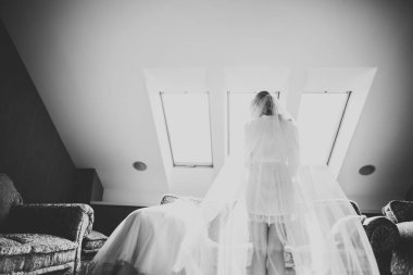 Cüppeli muhteşem gelin bir odada düğün töreni için poz veriyor ve hazırlanıyor.