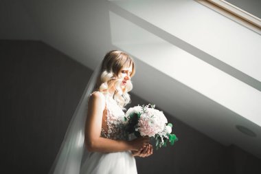 Beyaz elbiseli lüks gelin düğün törenine hazırlanırken poz veriyor.