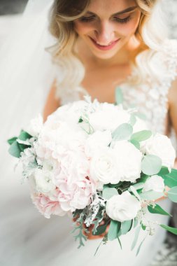 Çekici gelinin portresi, uzun saçlı, büyük buketli poz veren.