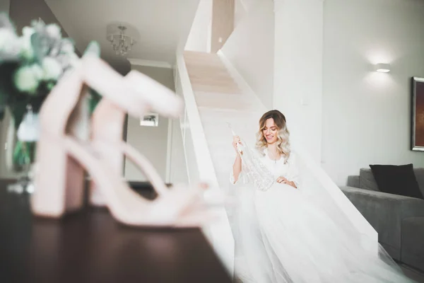 Preciosa novia en bata posando y preparándose para la ceremonia de boda cara en una habitación — Foto de Stock