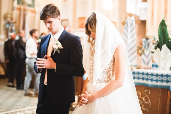 Casal casal posando em uma igreja após a cerimônia — Fotografia de Stock