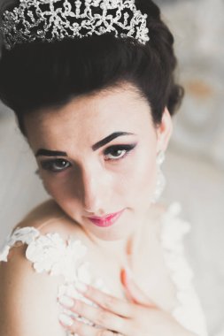 Cüppeli muhteşem gelin bir odada düğün töreni için poz veriyor ve hazırlanıyor.