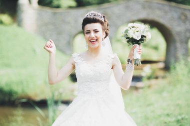 Çekici gelinin portresi, uzun saçlı, büyük buketli poz veren.