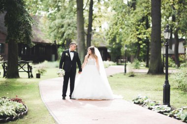 Yeni evli çift el ele tutuşurken parkta koşup zıplıyorlar.