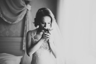 Cüppeli muhteşem gelin bir odada düğün töreni için poz veriyor ve hazırlanıyor.