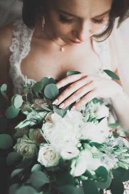 Cüppeli muhteşem gelin bir odada düğün töreni için poz veriyor ve hazırlanıyor.