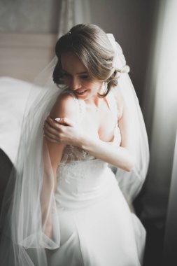 Cüppeli muhteşem gelin bir odada düğün töreni için poz veriyor ve hazırlanıyor.