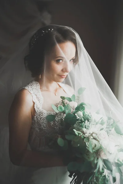 Preciosa novia en bata posando y preparándose para la ceremonia de boda cara en una habitación —  Fotos de Stock