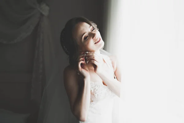 Linda noiva em roupão posando e se preparando para o rosto cerimônia de casamento em uma sala — Fotografia de Stock