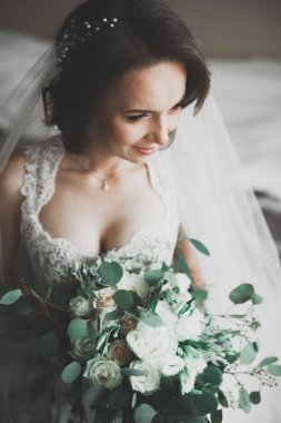 Cüppeli muhteşem gelin bir odada düğün töreni için poz veriyor ve hazırlanıyor.