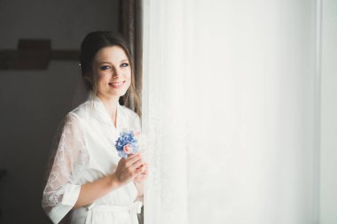 Beyaz elbiseli lüks gelin düğün törenine hazırlanırken poz veriyor.