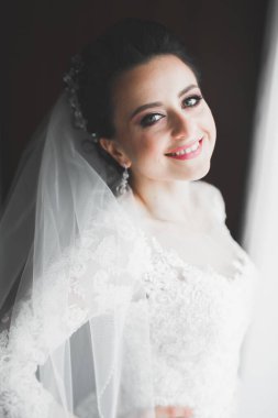 Cüppeli muhteşem gelin bir odada düğün töreni için poz veriyor ve hazırlanıyor.