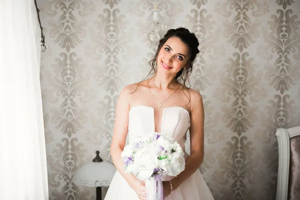 Bela noiva vestindo vestido de noiva de moda com penas com deleite de luxo maquiagem e penteado, estúdio sessão de fotos indoor — Fotografia de Stock