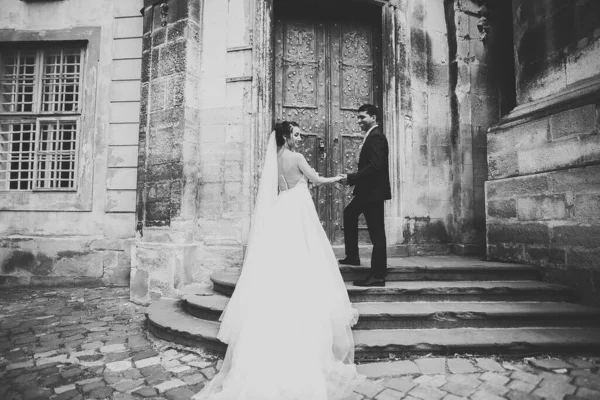 Preciosa pareja feliz de pie cerca el uno del otro y mirando a los ojos en el fondo de la ciudad vieja, foto de la boda, ciudad europea, día de la boda en Lviv —  Fotos de Stock
