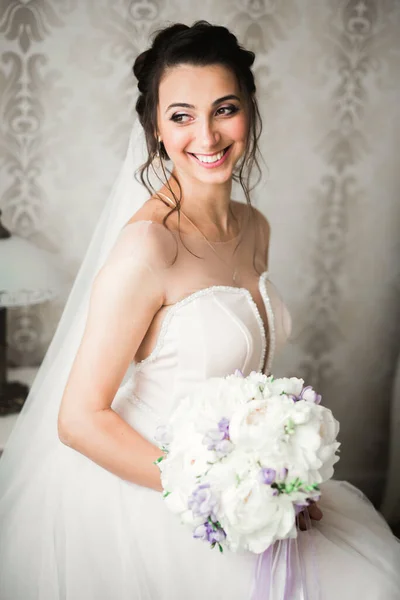 Beautiful bride wearing fashion wedding dress with feathers with luxury delight make-up and hairstyle, studio indoor photo shoot Stock Image