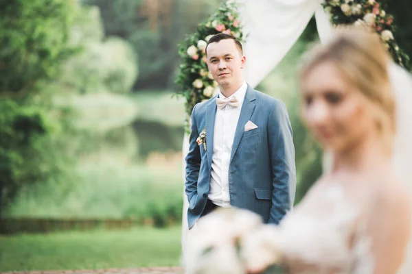 Beautiful bride and groom embracing and kissing on their wedding day outdoors — Stock Photo, Image