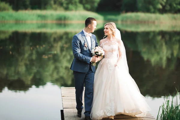 Mooie bruid en bruidegom omarmen en kussen op hun trouwdag buiten — Stockfoto