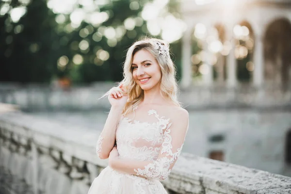 Bela noiva morena em vestido branco elegante segurando buquê posando perto do castelo — Fotografia de Stock