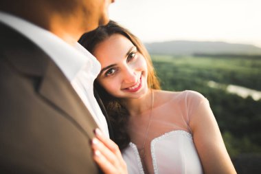 Doğadaki düğün çifti birbirine sarılıyor. Beyaz elbiseli güzel bir kız. Takım elbiseli adam