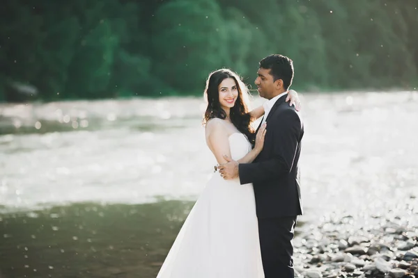 Düğün çifti, damat ve gelin kucaklaşıyor, nehir kenarında. — Stok fotoğraf