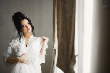 Cüppeli muhteşem gelin bir odada düğün töreni için poz veriyor ve hazırlanıyor.