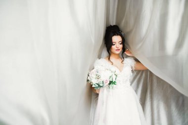 Gelin çiçekli büyük ve güzel bir düğün buketi tutuyor.