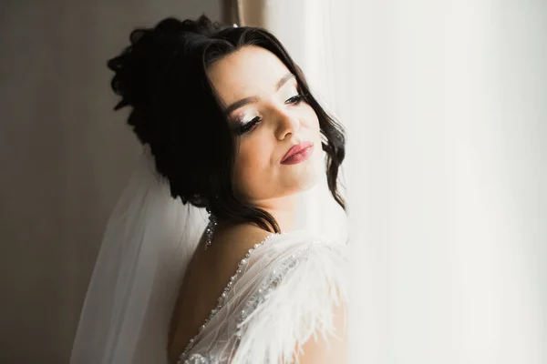 Belle mariée portant une robe de mariée de mode avec des plumes avec luxe délice maquillage et coiffure, studio séance photo d'intérieur — Photo
