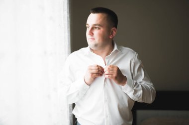 Güzel adam, damat poz veriyor ve düğüne hazırlanıyor.