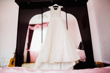 Gelinin odasındaki askıda uzun etekli mükemmel gelinlik.