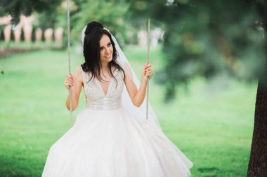 Parkta poz veren gelinlikli güzel, lüks bir gelin.