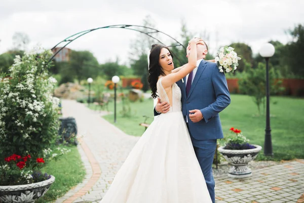 Beau jeune couple de mariage posant avec bouquet de fleurs dans les mains — Photo